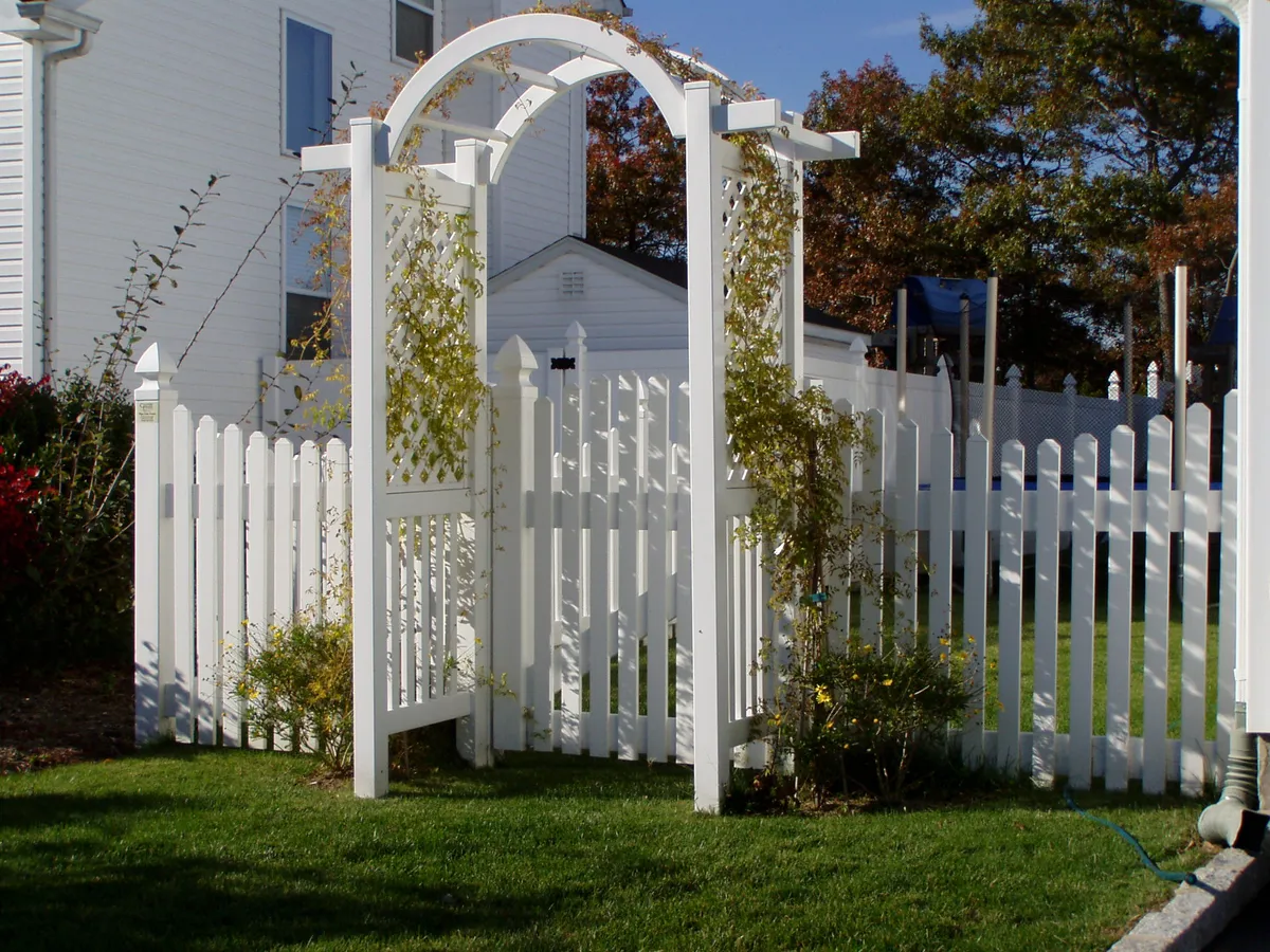 White PVC arbor with arched top and picket fence gate